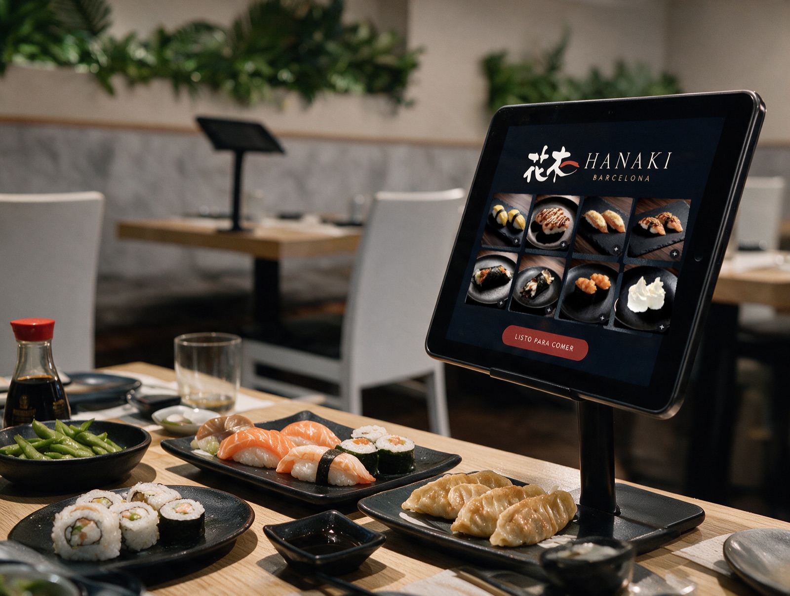 Tablet de pedidos Hanaki Barcelona en la mesa, con sushi y gyozas